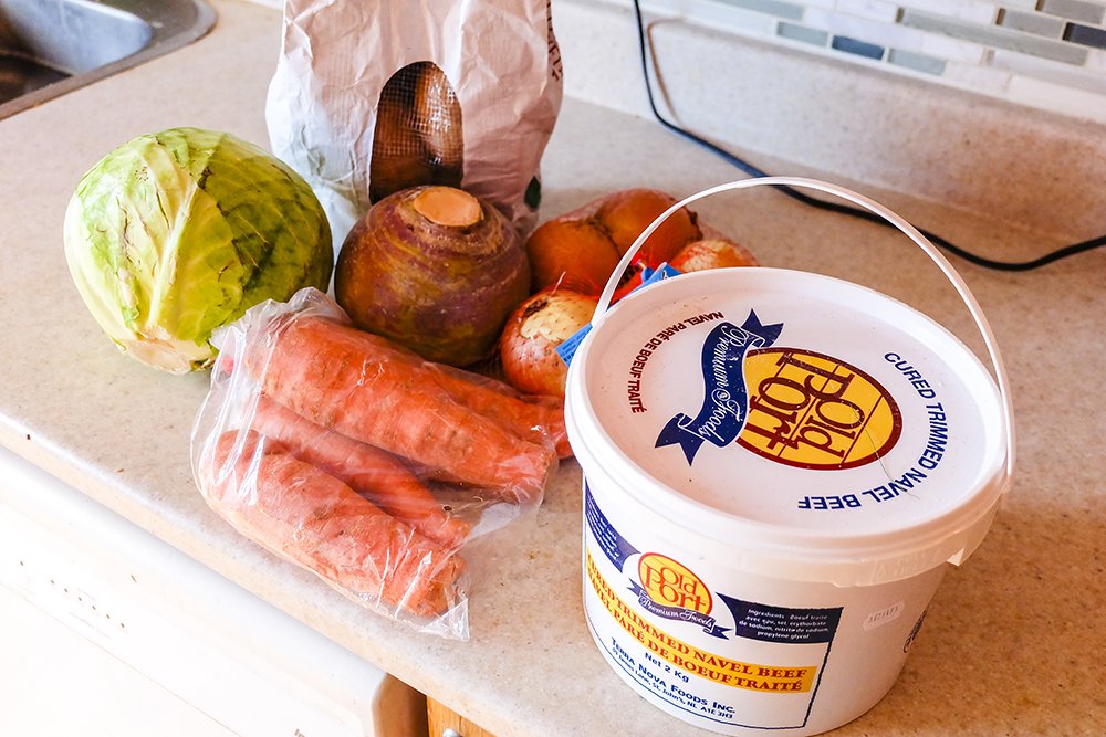 Picture of raw cabbage, carrots, a turnip, onions, and a bucket of Old Port salt beef.